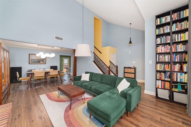 3 Whistlers Walk Pl, The Woodlands, TX 77381 - living area featuring wood finished floors, stairway, high vaulted ceiling, a chandelier, and built in shelves