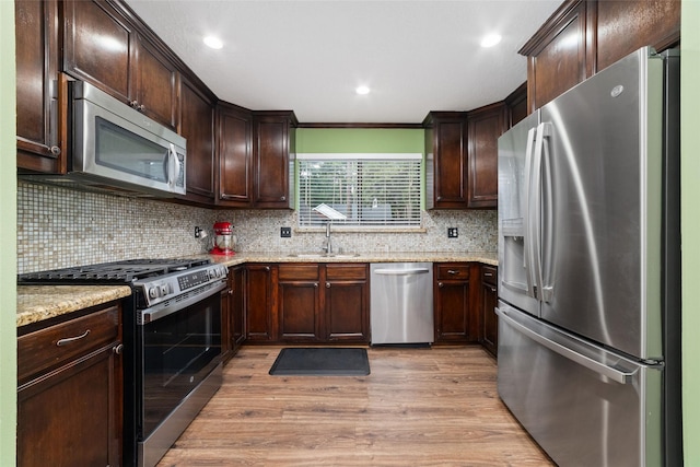 3 Whistlers Walk Pl, The Woodlands, TX 77381 - kitchen featuring stainless steel appliances, dark brown cabinetry, light wood-type flooring, decorative backsplash, and ornamental molding