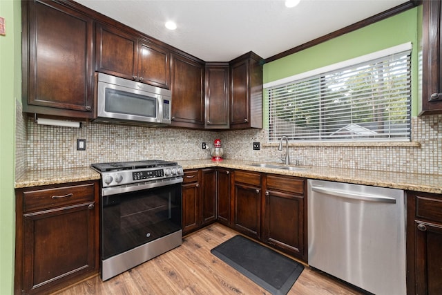 3 Whistlers Walk Pl, The Woodlands, TX 77381 - kitchen featuring appliances with stainless steel finishes, light wood-type flooring, dark brown cabinets, tasteful backsplash, and crown molding