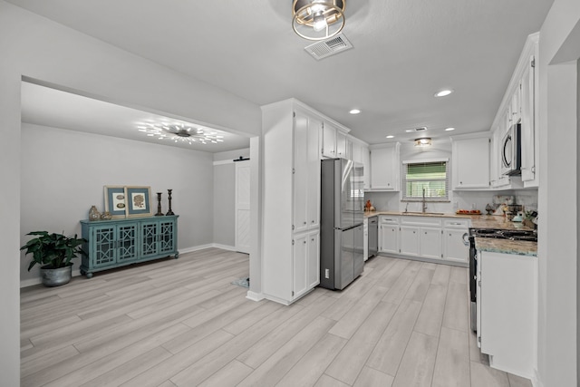 5709 David St, Dickinson, TX 77539 - kitchen featuring stainless steel appliances, white cabinetry, light wood finished floors, and recessed lighting