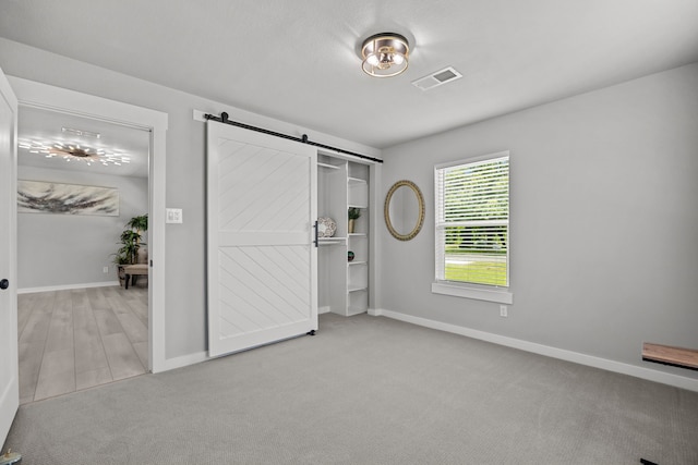 5709 David St, Dickinson, TX 77539 - unfurnished bedroom with a barn door and carpet