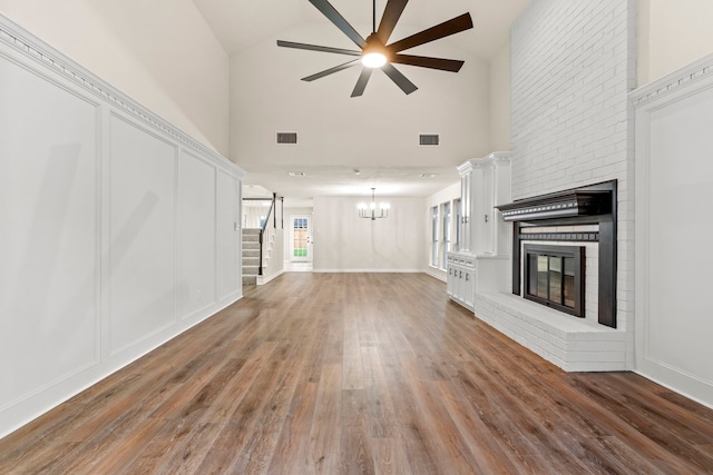 12135 Quail Creek Dr, Houston, TX 77070 - unfurnished living room with high vaulted ceiling, a brick fireplace, ceiling fan, stairs, and a chandelier