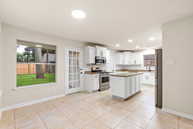 12135 Quail Creek Dr, Houston, TX 77070 - kitchen with stainless steel appliances, white cabinetry, recessed lighting, a center island, and light tile patterned flooring