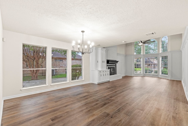 12135 Quail Creek Dr, Houston, TX 77070 - unfurnished living room with a chandelier, a textured ceiling, wood finished floors, a ceiling fan, and a fireplace