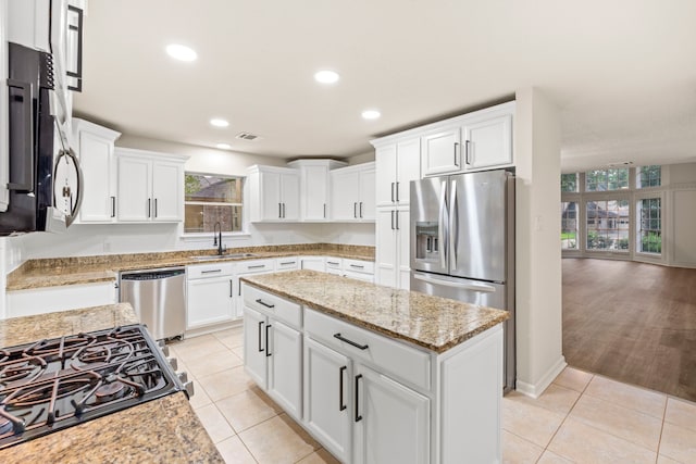 12135 Quail Creek Dr, Houston, TX 77070 - kitchen with appliances with stainless steel finishes, white cabinets, light stone counters, a kitchen island, and recessed lighting