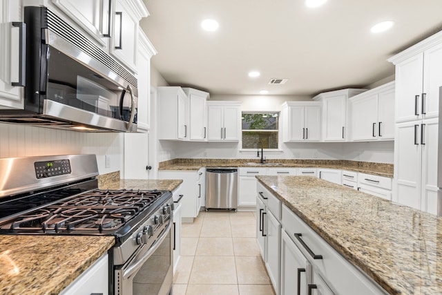 12135 Quail Creek Dr, Houston, TX 77070 - kitchen with stainless steel appliances, white cabinets, light tile patterned floors, recessed lighting, and light stone counters