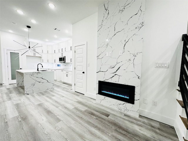 5042 Pershing St Unit Ab, Houston, TX 77033 - unfurnished living room featuring recessed lighting, light wood-style floors, a premium fireplace, and a chandelier