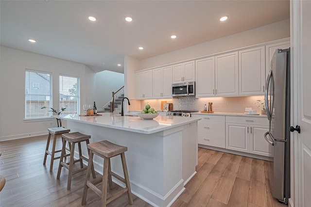 16819 Chapel Knox Dr, Humble, TX 77346 - kitchen with appliances with stainless steel finishes, white cabinets, a breakfast bar area, light wood-style flooring, and recessed lighting