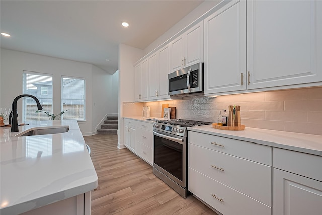 16819 Chapel Knox Dr, Humble, TX 77346 - kitchen featuring appliances with stainless steel finishes, light wood finished floors, white cabinetry, light countertops, and recessed lighting