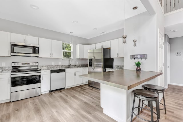 561 N Royale Greens Dr, Coldspring, TX 77331 - kitchen with appliances with stainless steel finishes, a kitchen bar, a peninsula, white cabinetry, and recessed lighting