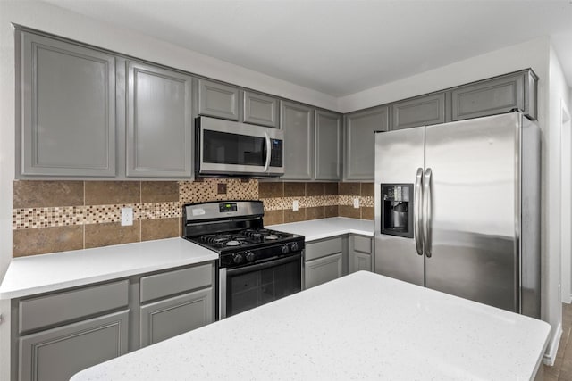9987 Sterling Place Dr, Conroe, TX 77303 - kitchen with stainless steel appliances, gray cabinets, and decorative backsplash