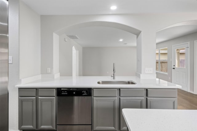 9987 Sterling Place Dr, Conroe, TX 77303 - kitchen with stainless steel dishwasher, arched walkways, gray cabinets, light countertops, and a peninsula