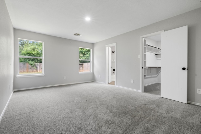 9987 Sterling Place Dr, Conroe, TX 77303 - unfurnished bedroom featuring carpet flooring, multiple windows, a spacious closet, ensuite bathroom, and recessed lighting