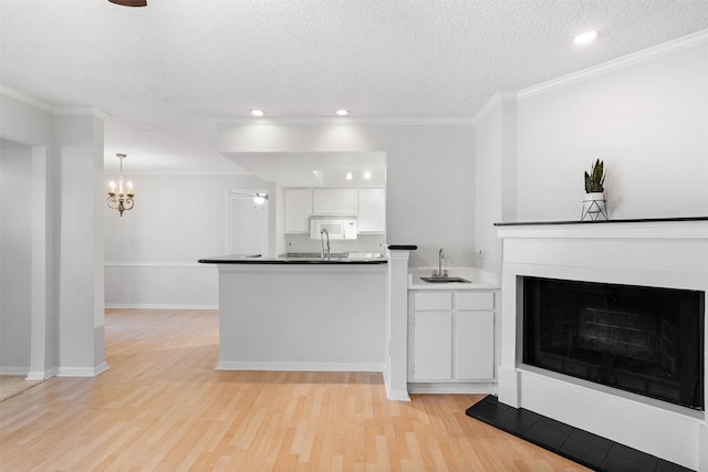 2800 Jeanetta St Unit 2502, Houston, TX 77063 - kitchen featuring white cabinets, a peninsula, a textured ceiling, light wood finished floors, and crown molding