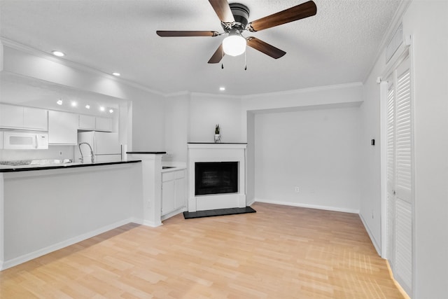 2800 Jeanetta St Unit 2502, Houston, TX 77063 - unfurnished living room featuring light wood-style flooring, ceiling fan, crown molding, recessed lighting, and a fireplace with raised hearth