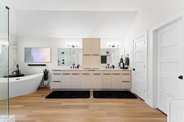 10826 Moonlight Dr, Houston, TX 77096 - bathroom featuring double vanity, a freestanding bath, a shower with door, vaulted ceiling, and wood finished floors