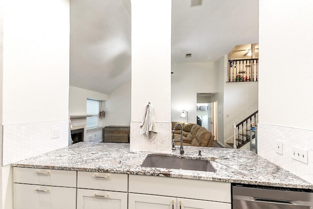 12223 Paddock Way, Houston, TX 77065 - kitchen with stainless steel dishwasher, light stone counters, open floor plan, tasteful backsplash, and white cabinetry