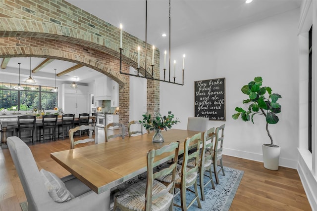 37732 Marias Way, Magnolia, TX 77354 - dining area featuring arched walkways, wood finished floors, a towering ceiling, recessed lighting, and brick wall