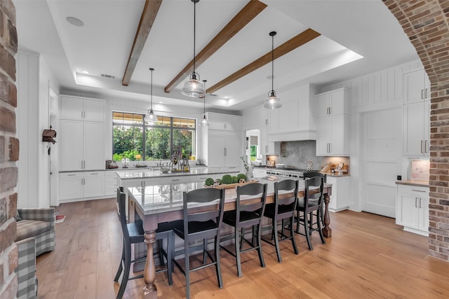 37732 Marias Way, Magnolia, TX 77354 - dining space featuring light wood-type flooring, beamed ceiling, and brick wall