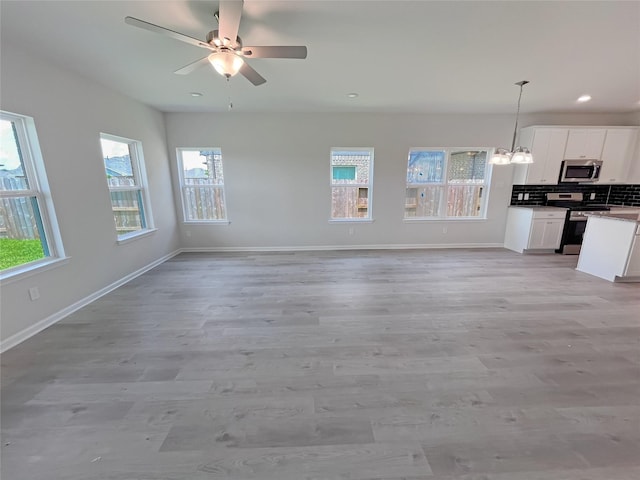 32402 Fly Fish Way, Fulshear, TX 77441 - unfurnished living room featuring light wood finished floors, recessed lighting, a ceiling fan, and a chandelier
