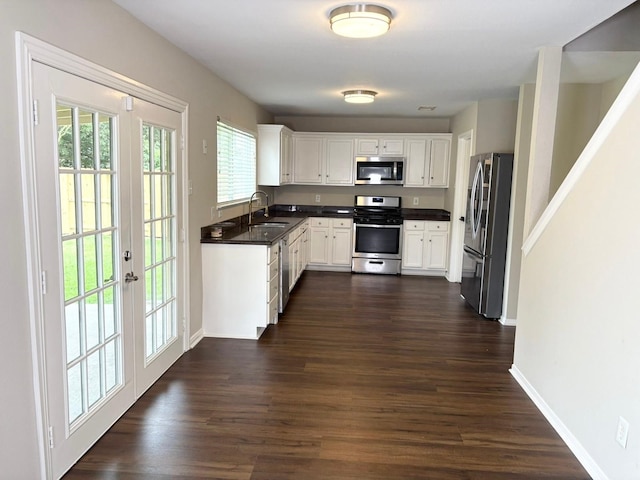 3403 Fox Ct, Pearland, TX 77581 - kitchen with appliances with stainless steel finishes, dark countertops, dark wood-style flooring, white cabinets, and french doors