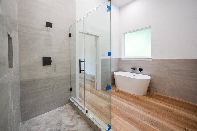 8703 Miller Rd, Magnolia, TX 77354 - bathroom with a stall shower, tile walls, a soaking tub, and wainscoting