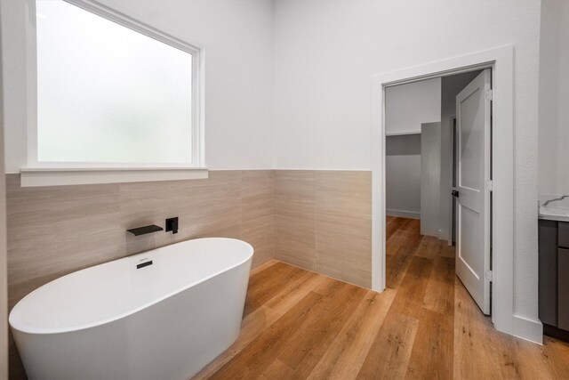 8703 Miller Rd, Magnolia, TX 77354 - full bathroom with a freestanding tub, tile walls, wood finished floors, vanity, and wainscoting