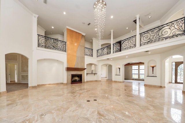 1743 Randons Point Dr, Sugar Land, TX 77478 - unfurnished living room with a towering ceiling, light marble finish floors, a large fireplace, crown molding, and a chandelier