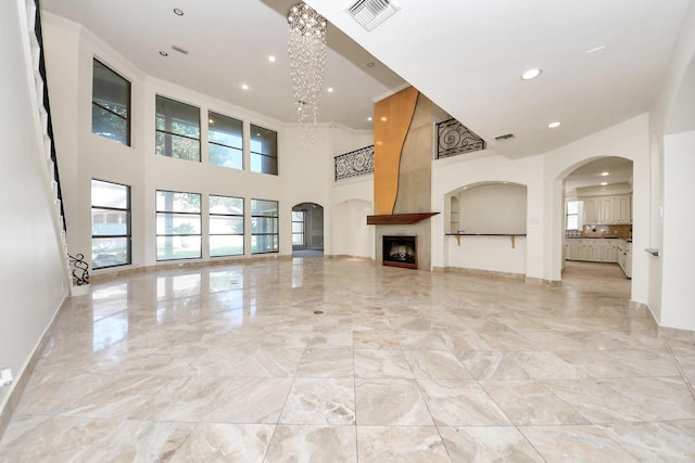 1743 Randons Point Dr, Sugar Land, TX 77478 - unfurnished living room with a towering ceiling, healthy amount of natural light, light marble finish floors, recessed lighting, and arched walkways