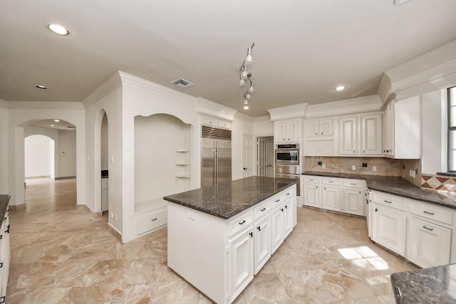 1743 Randons Point Dr, Sugar Land, TX 77478 - kitchen with built in refrigerator, a center island, arched walkways, decorative backsplash, and dark stone countertops