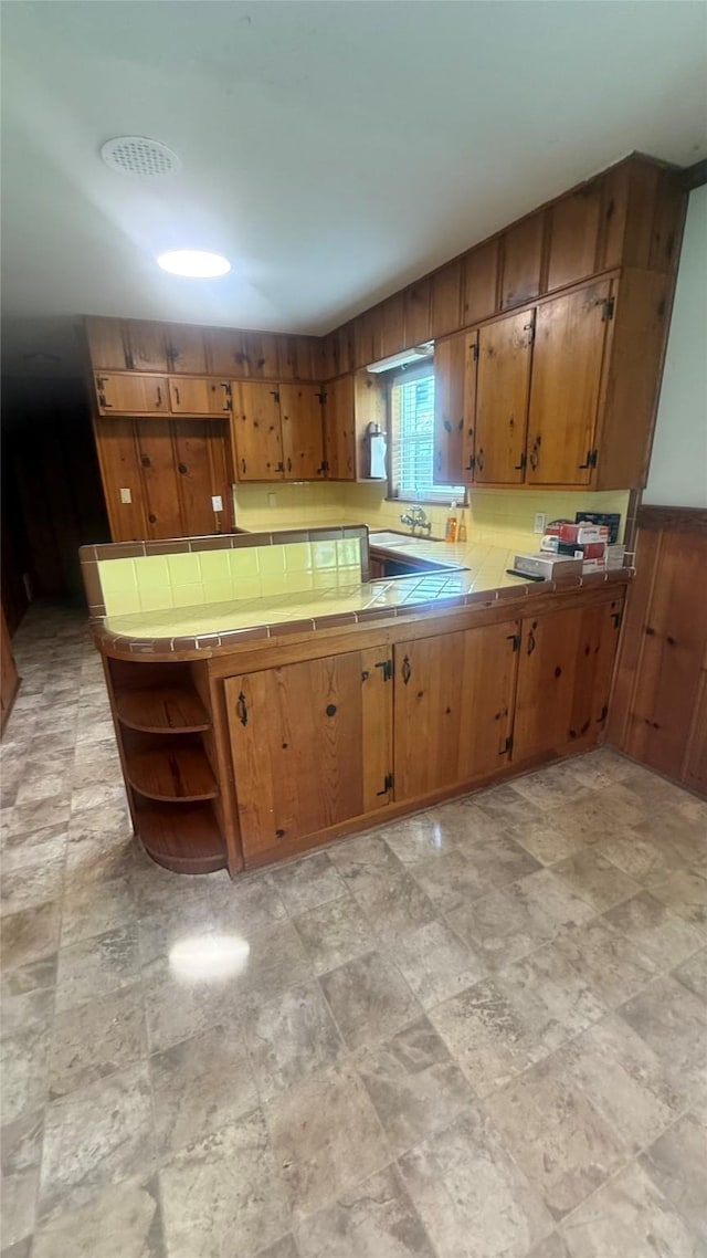 5580 Hooks Ave, Beaumont, TX 77706 - kitchen featuring tile countertops, open shelves, brown cabinets, and stone finish floors
