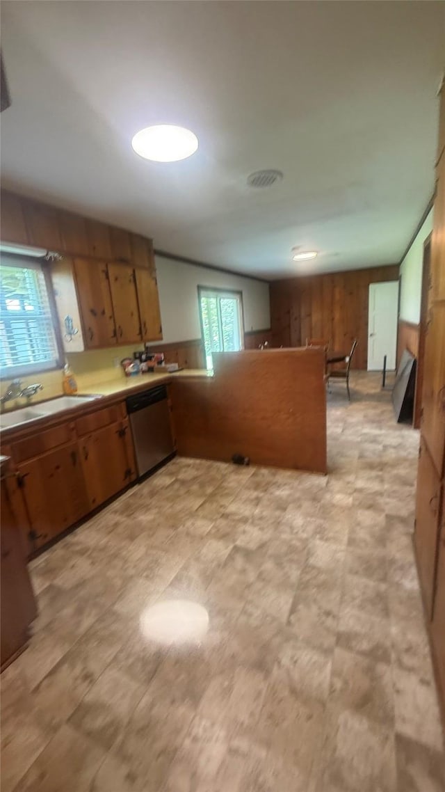 5580 Hooks Ave, Beaumont, TX 77706 - kitchen with stainless steel dishwasher, brown cabinets, a peninsula, wooden walls, and light countertops