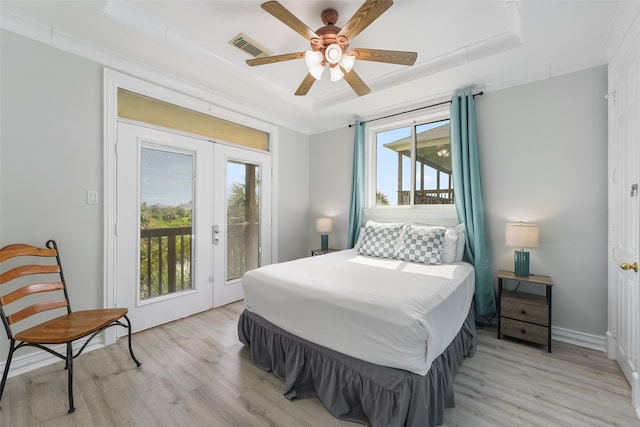 22517 Bay Point Dr, Galveston, TX 77554 - bedroom featuring a tray ceiling, light wood-style floors, french doors, access to exterior, and a ceiling fan