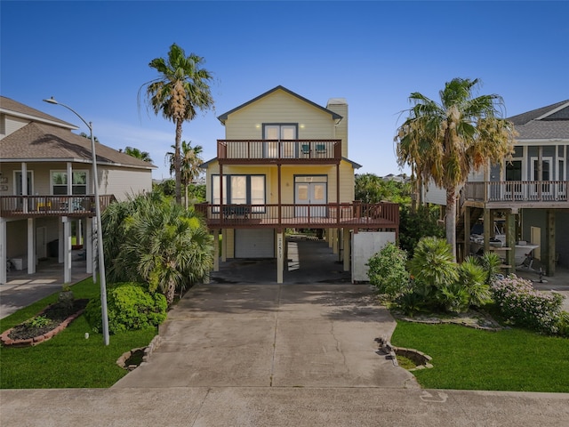 22517 Bay Point Dr, Galveston, TX 77554 - coastal home with a balcony, a carport, concrete driveway, an attached garage, and a front yard