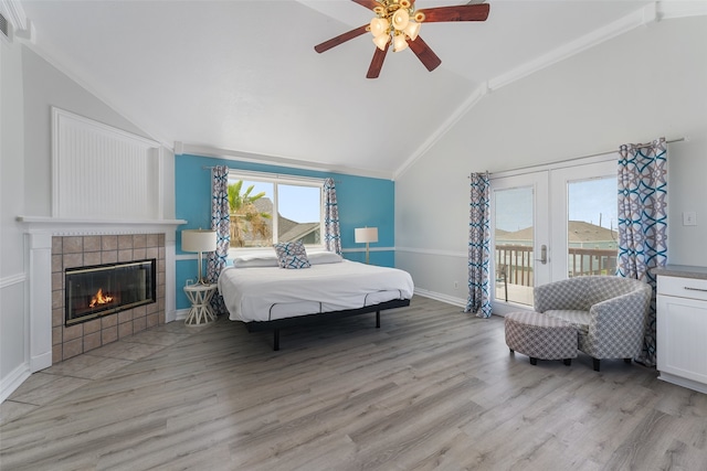 22517 Bay Point Dr, Galveston, TX 77554 - bedroom with lofted ceiling, access to exterior, light wood finished floors, a tiled fireplace, and ceiling fan