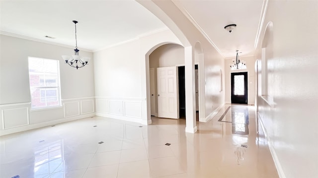 24714 Colonial Maple Dr, Katy, TX 77493 - tiled empty room featuring a chandelier, crown molding, wainscoting, arched walkways, and a decorative wall
