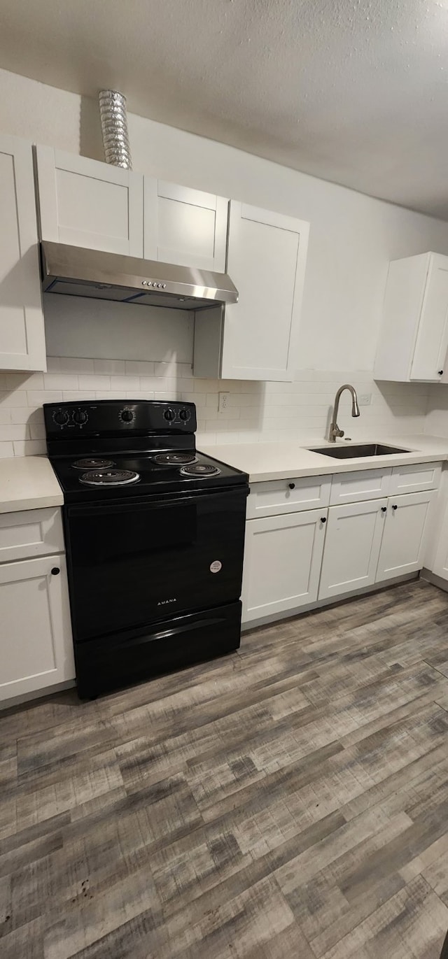 3655 Seabrook St, Houston, TX 77021 - kitchen with black electric range oven, range hood, white cabinetry, and decorative backsplash