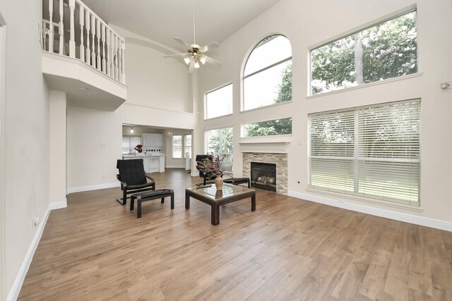 3622 Stratford Town Ln, Sugar Land, TX 77498 - living room featuring a stone fireplace, a high ceiling, wood finished floors, and a ceiling fan
