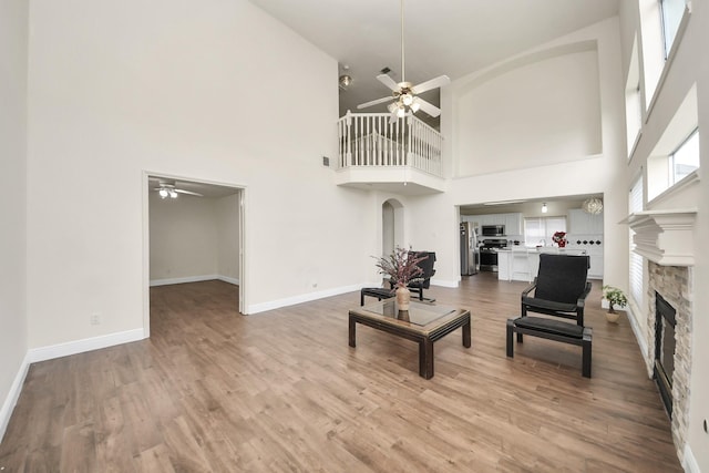 3622 Stratford Town Ln, Sugar Land, TX 77498 - living room with a ceiling fan, a stone fireplace, a high ceiling, and light wood finished floors