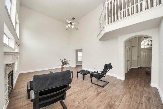 3622 Stratford Town Ln, Sugar Land, TX 77498 - living area featuring arched walkways, a high ceiling, wood finished floors, a stone fireplace, and ceiling fan