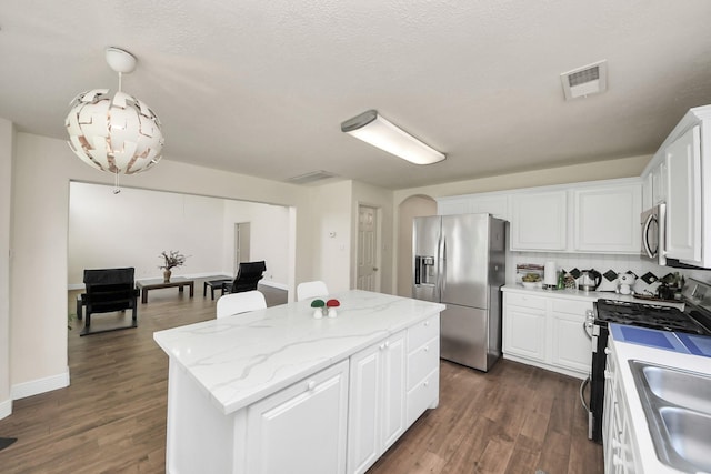 3622 Stratford Town Ln, Sugar Land, TX 77498 - kitchen with stainless steel appliances, a center island, white cabinetry, dark wood-style flooring, and arched walkways