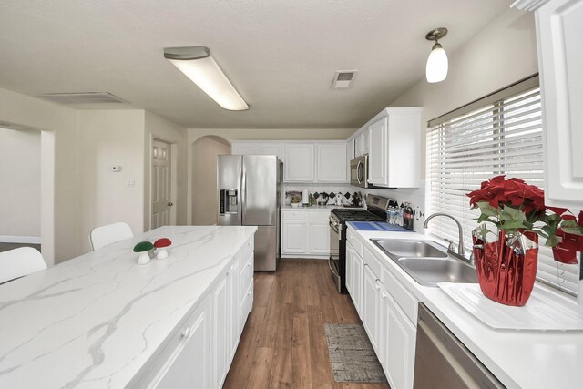 3622 Stratford Town Ln, Sugar Land, TX 77498 - kitchen with stainless steel appliances, white cabinets, arched walkways, dark wood-style floors, and light stone countertops