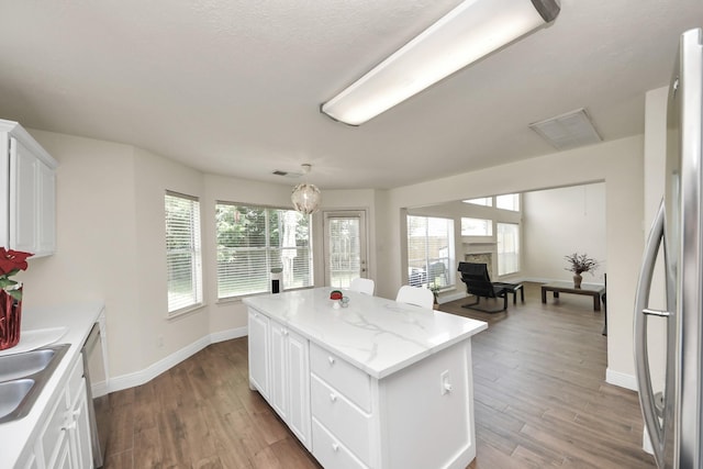 3622 Stratford Town Ln, Sugar Land, TX 77498 - kitchen with plenty of natural light, a kitchen island, light wood-type flooring, and white cabinets