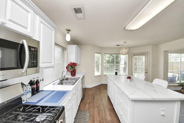 3622 Stratford Town Ln, Sugar Land, TX 77498 - kitchen featuring stainless steel appliances, a kitchen island, backsplash, white cabinetry, and dark wood-style flooring