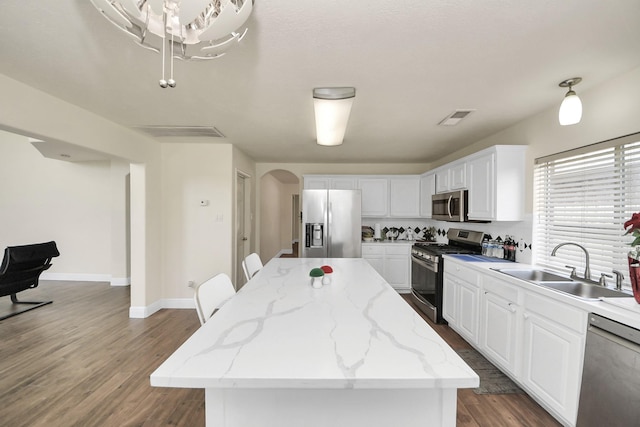 3622 Stratford Town Ln, Sugar Land, TX 77498 - kitchen featuring appliances with stainless steel finishes, arched walkways, a center island, and white cabinetry