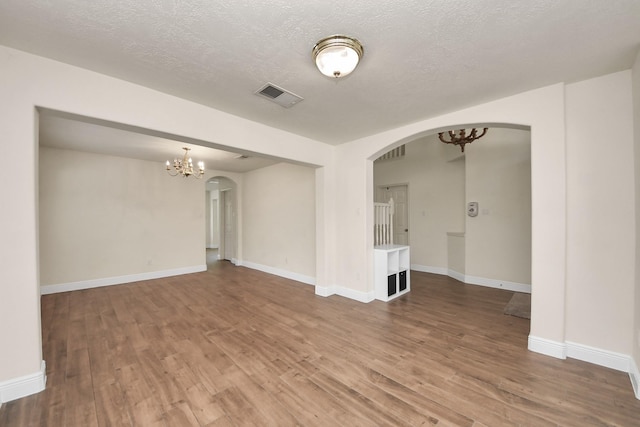 3622 Stratford Town Ln, Sugar Land, TX 77498 - empty room featuring arched walkways, a chandelier, wood finished floors, and a textured ceiling