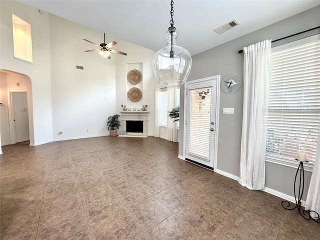 16506 Orchid Mist Dr, Cypress, TX 77433 - unfurnished living room with arched walkways, a ceiling fan, plenty of natural light, and a fireplace with raised hearth