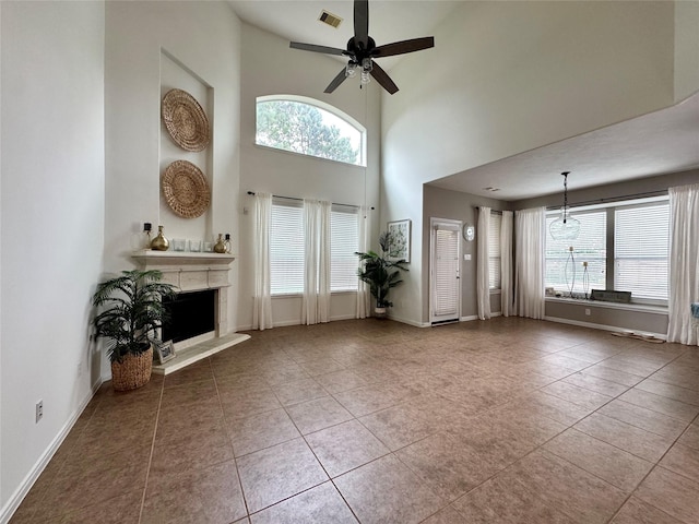 16506 Orchid Mist Dr, Cypress, TX 77433 - unfurnished living room with a ceiling fan, healthy amount of natural light, a fireplace with raised hearth, a towering ceiling, and tile patterned floors