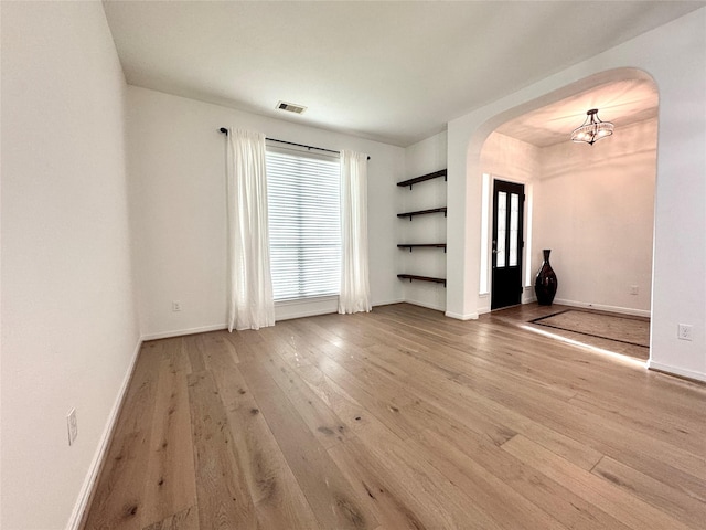 16506 Orchid Mist Dr, Cypress, TX 77433 - empty room featuring arched walkways, hardwood / wood-style flooring, a chandelier, and built in shelves