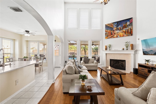 23602 Hawkins Creek Ct, Katy, TX 77494 - living room featuring a towering ceiling, a ceiling fan, arched walkways, a fireplace, and plenty of natural light